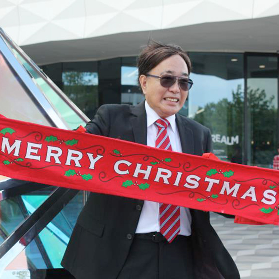 Jeffrey Gung Jeffrey is smiling and holding a Merry Christmas banner.