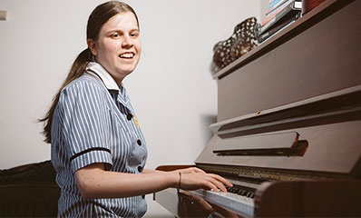 Blind girl in school uniform playing piano