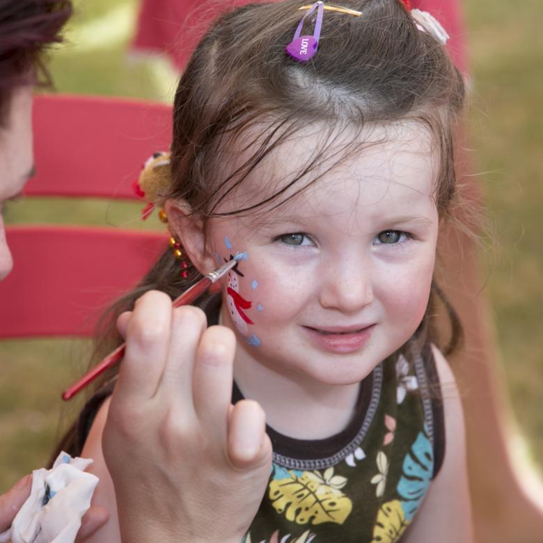 photo of a young girl smiling whilst getting her face painted