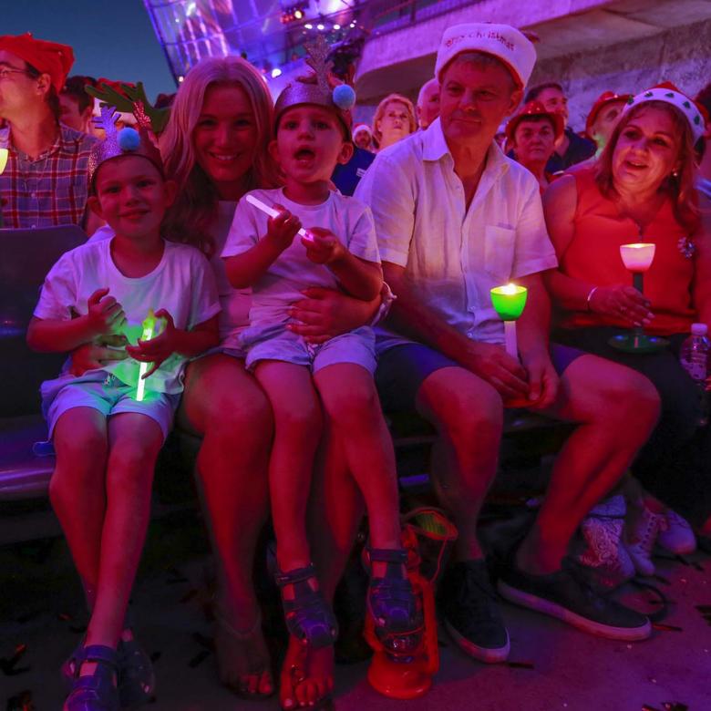 photo of a family sitting in the audience holding their glowing candles and looking happy