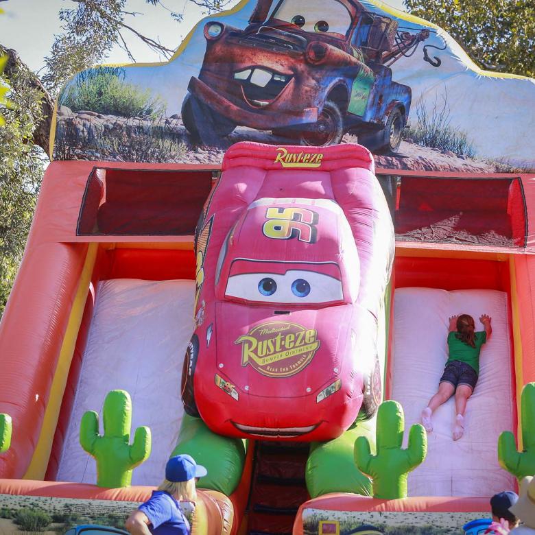 Photo of an inflatable slide for children with an animated character on it. There is a child sliding down.