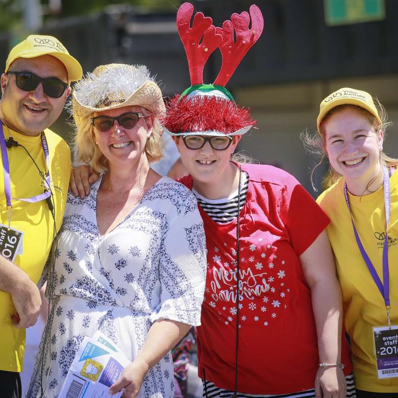 Photo of volunteer event staff wearing yellow branded T-shirt and carols guests looking happy