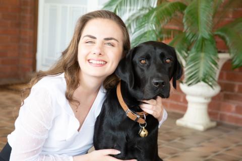 Lara Nakhle with her arm around a black Labrador