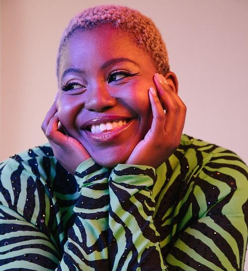 Thando wears a green and black top, smiling