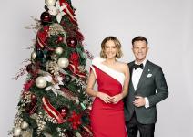Brooke Boney wearing a red dress, stands next to David Campbell in a black suit in front of a Christmas tree