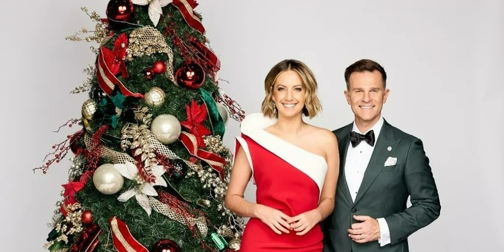 Brooke Boney and David Campbell stand beside a Christmas tree, smiling
