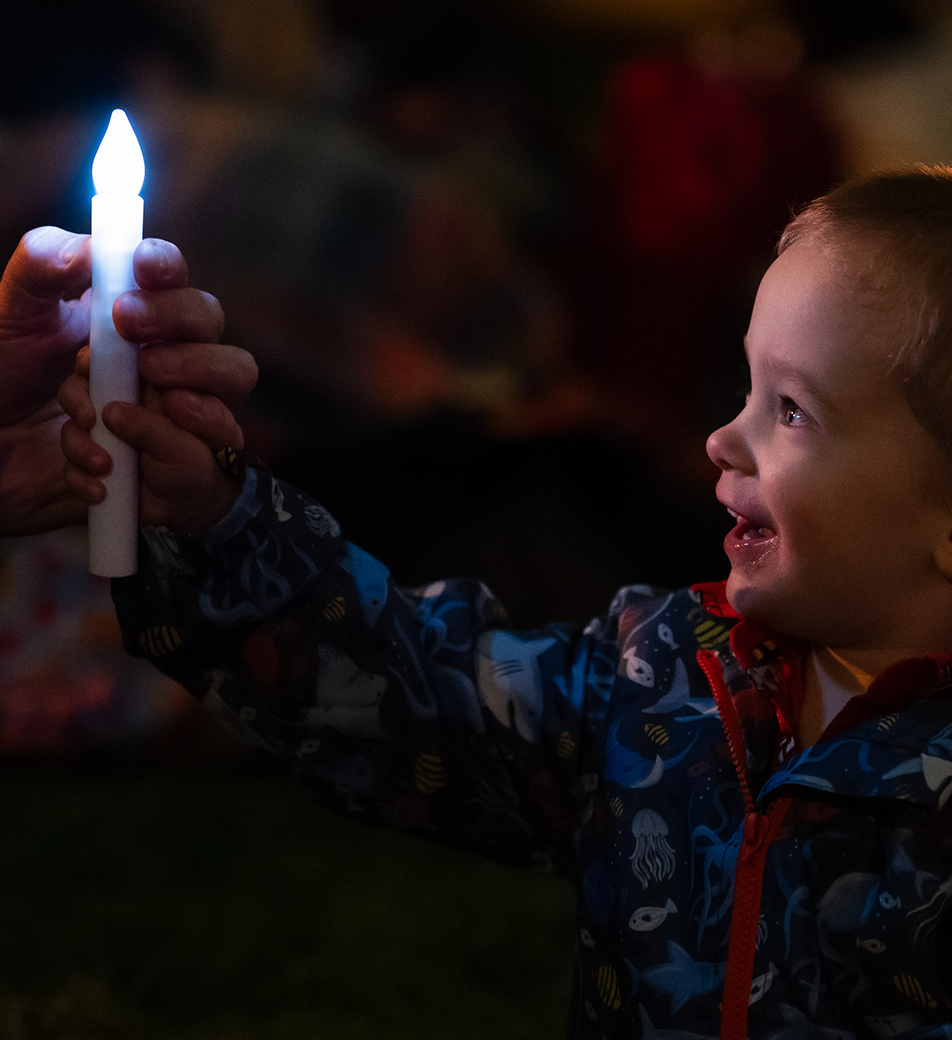 Child smiling holding up a candle glowstick
