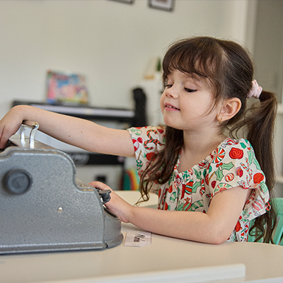 Marlee sits at a table with a brailler