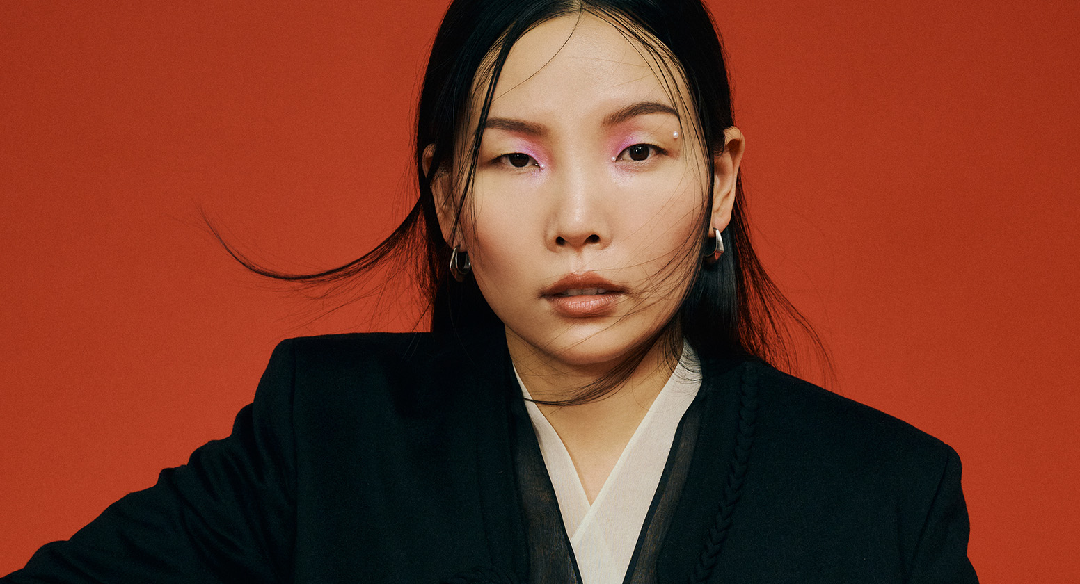 Dami Im wears a black jacket against a red background