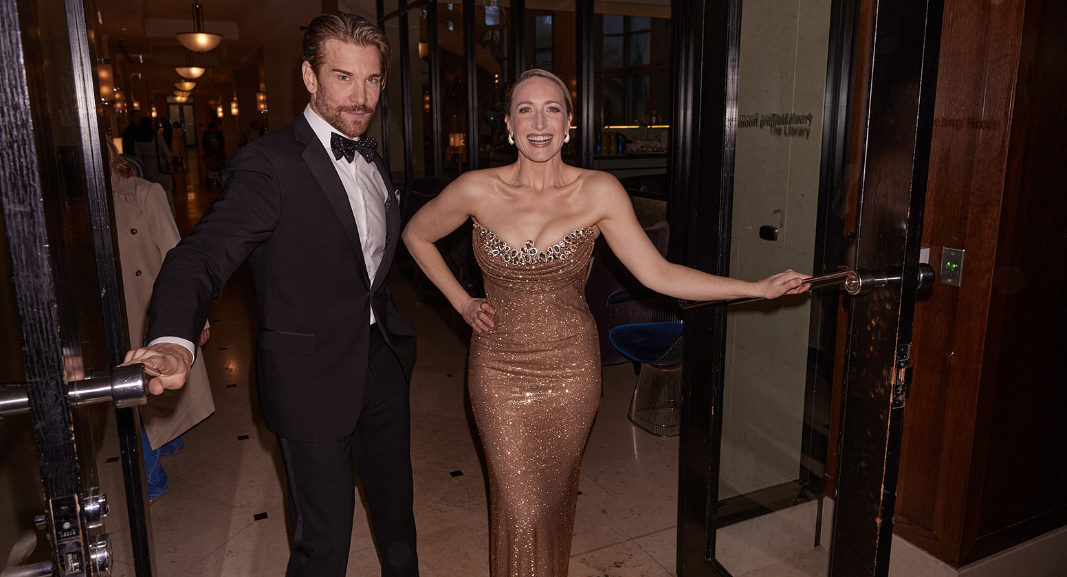Andy Karl and Elise McCann wearing formal attire in a doorway