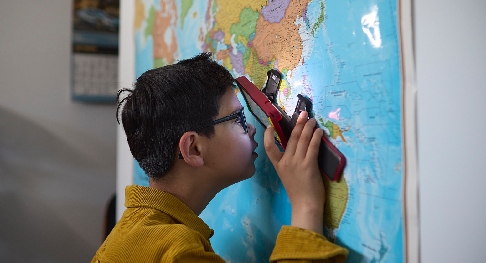 Mikail looks through a magnifier at a map on the wall