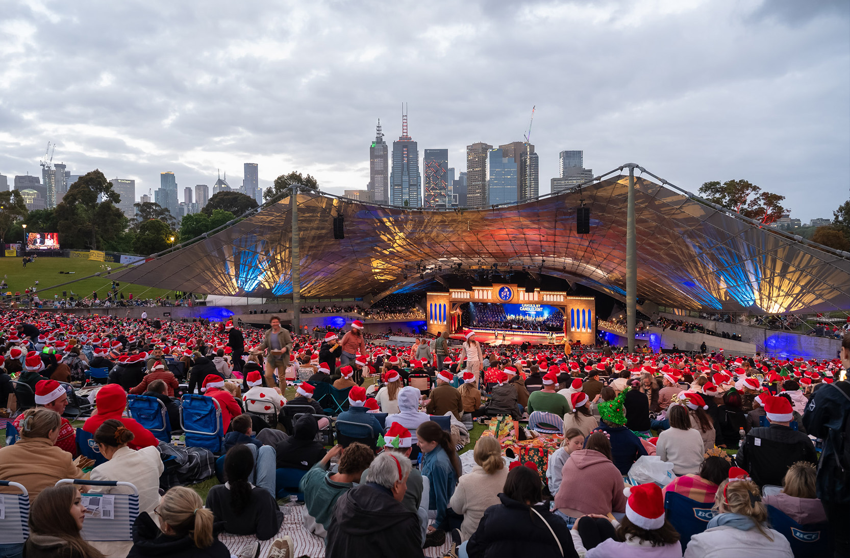 Sidney Myer Music Bowl during Carols by Candlelight, with audience seated and Melbourne skyline in the distance