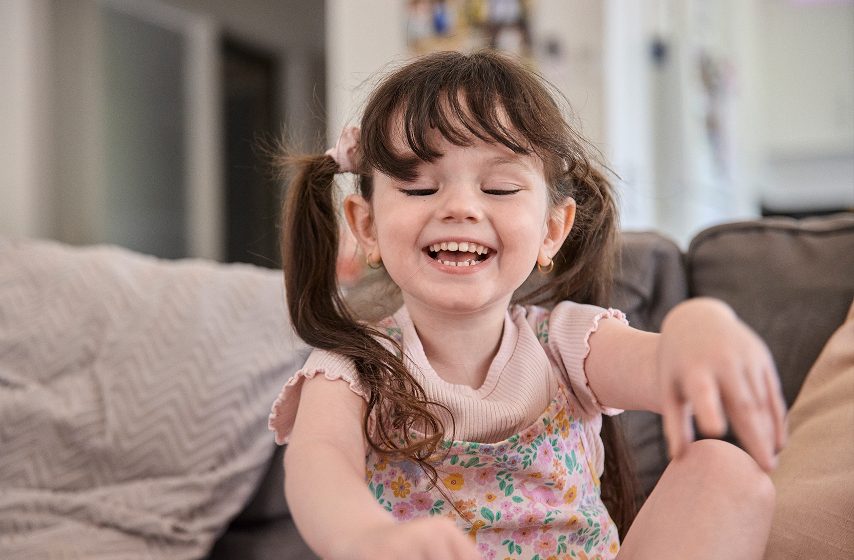 A young girl sits on a couch smiling