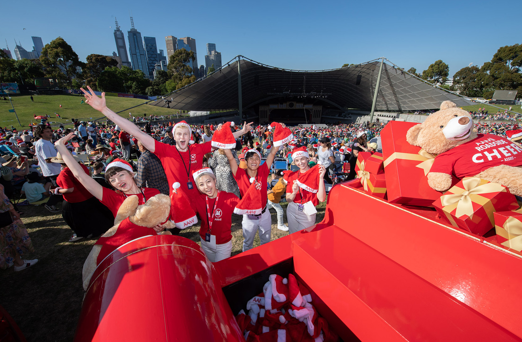AAMI Cheer Van and staff cheering with the Carols crowd and stage behind them