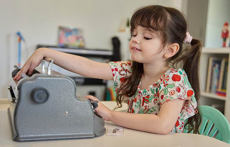 Marlee sits at a table with a brailler