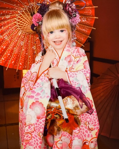 Young blonde girl dressed in traditional japanese clothing smiling